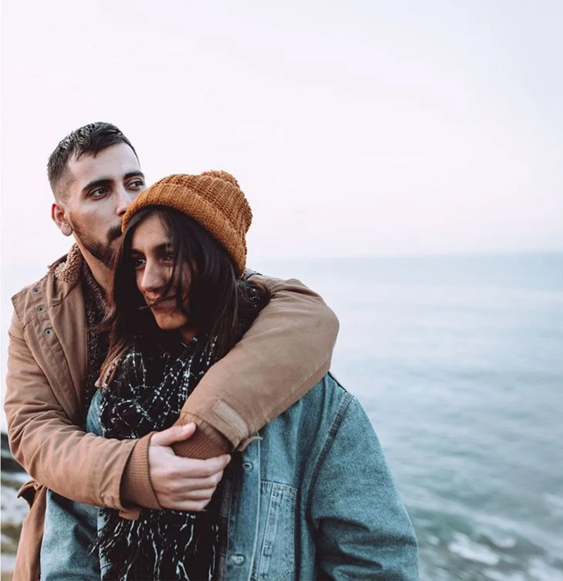 Couple snuggling by ocean