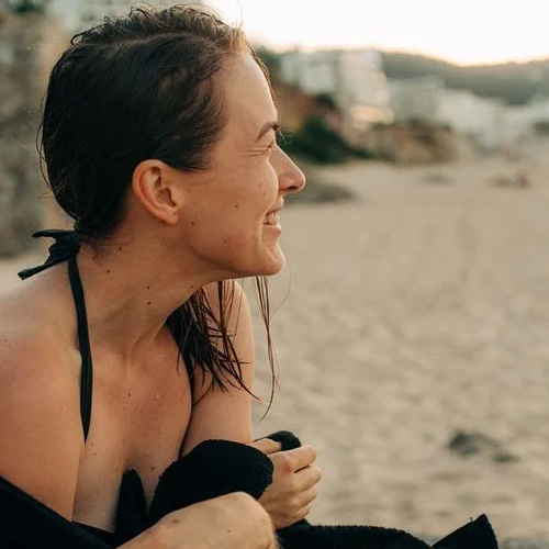 Woman sitting on beach wrapped in a towel