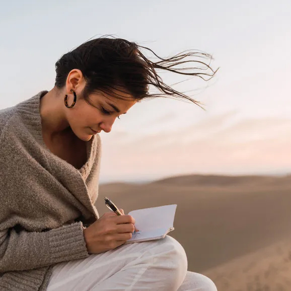 Woman writing in notebook at beach
