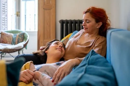 Daughter lying on mothers lap, smiling up at her